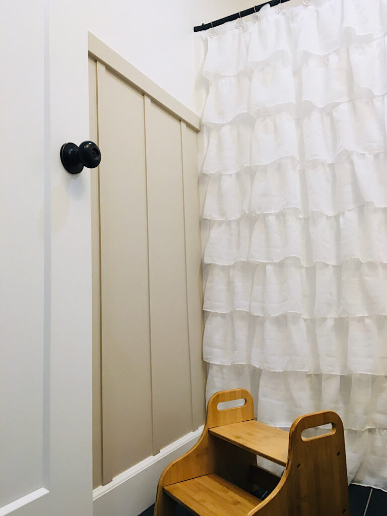 board and batten accent wall in bathroom with curtain