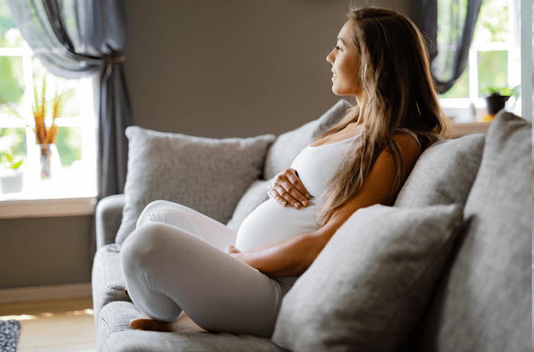 Pregnant woman on couch holding belly